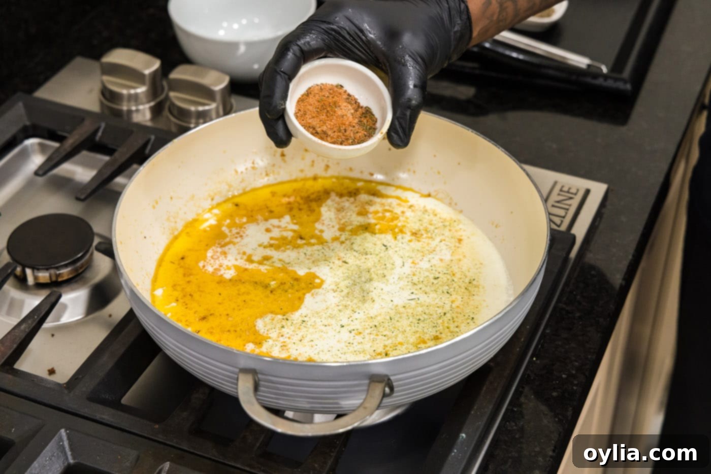adding cajun seasoning to cream sauce in skillet