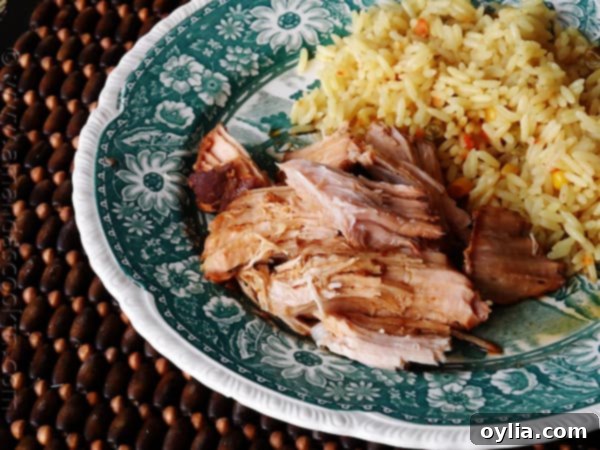 A close up photo of a delicious Slow Cooker Oriental Pork Roast on a plate next to fluffy rice, showcasing the tender texture.
