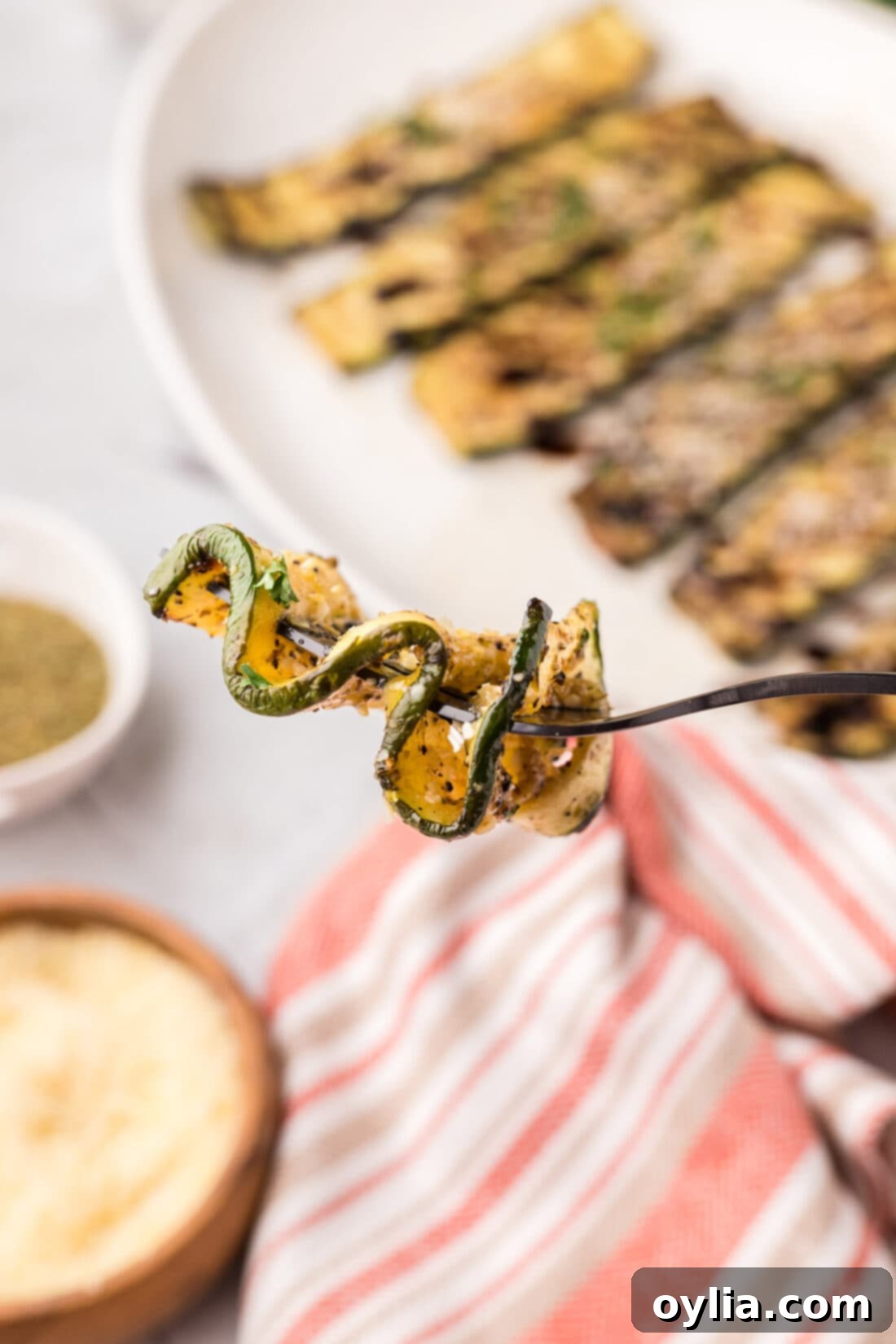 Perfectly grilled zucchini slice zig-zagged on a fork, showing tender texture and light char marks.