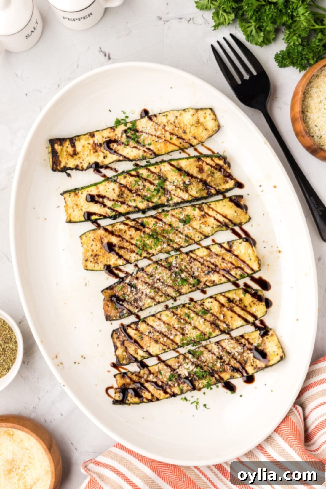 Platter of perfectly grilled zucchini topped with a glistening balsamic glaze.