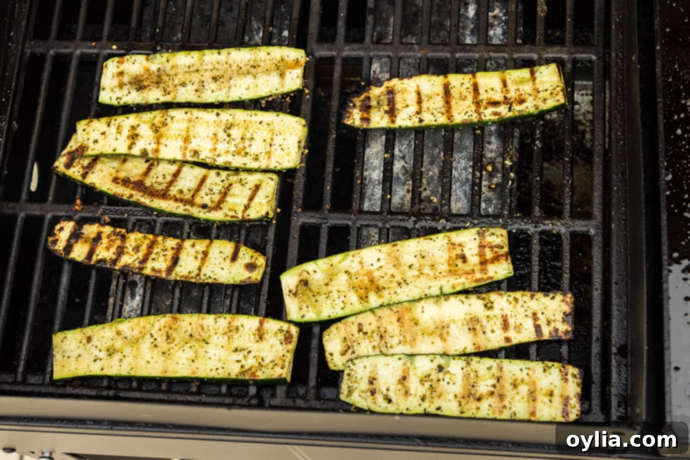 Close-up of grilled zucchini slices with perfect char marks on the grill grates.