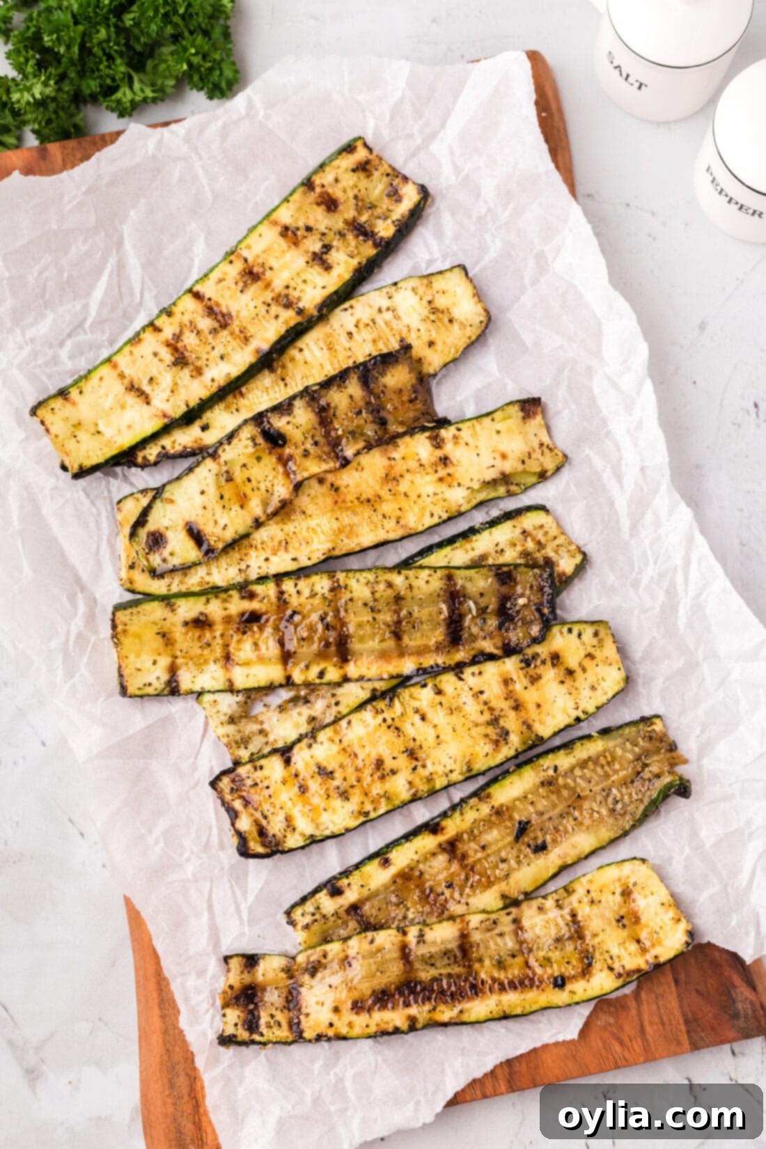 Beautifully arranged grilled zucchini on a wooden platter with parchment paper, ready to serve.