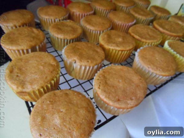 Freshly baked carrot cupcakes cooling on a wire rack, ready for frosting.