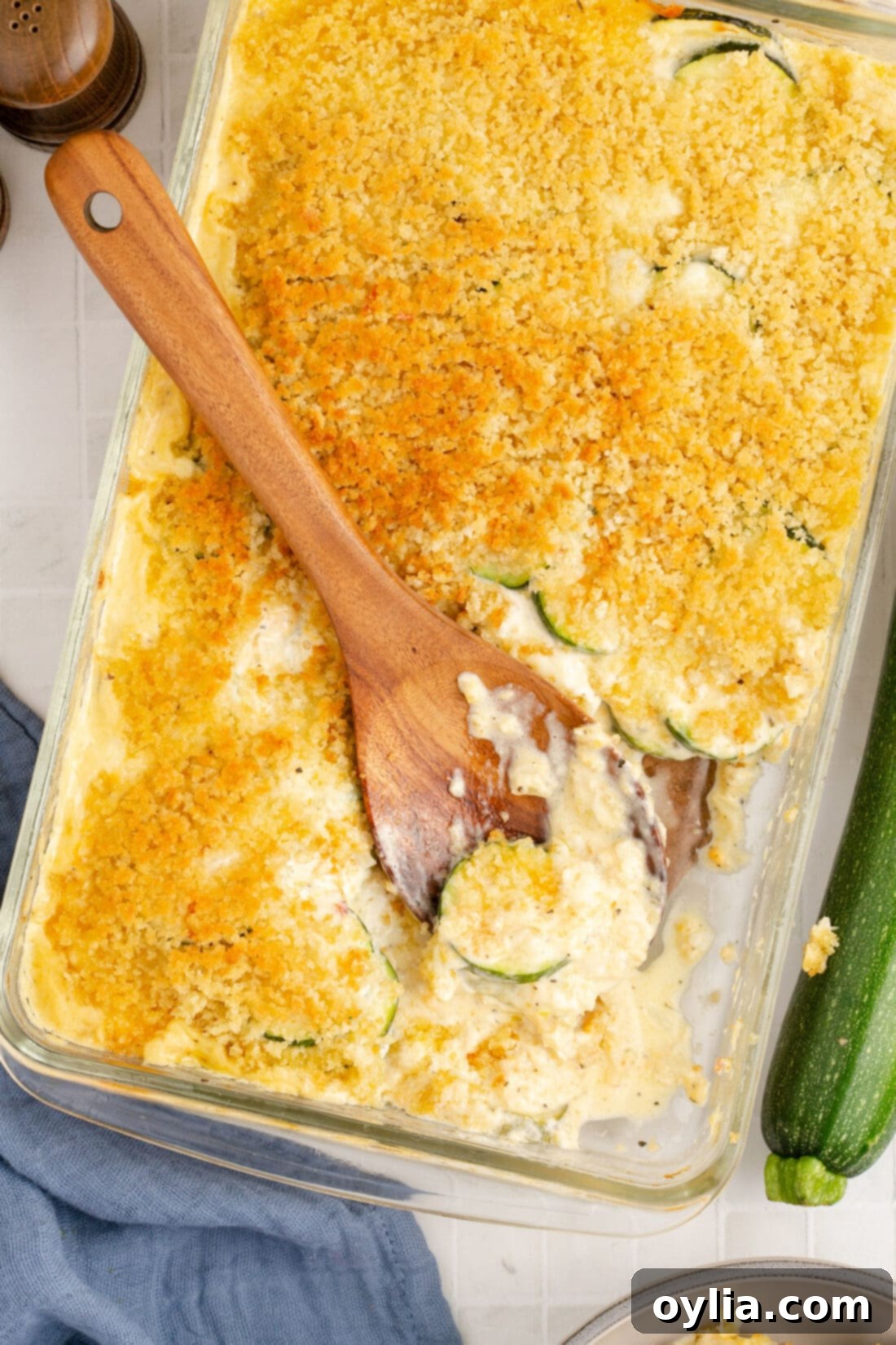 Spoon resting in a pan of a golden brown, bubbly Zucchini Casserole, ready to be served.
