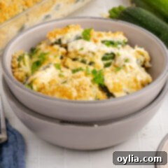 A bowl of hot, cheesy Zucchini Casserole with a fork, ready to eat.