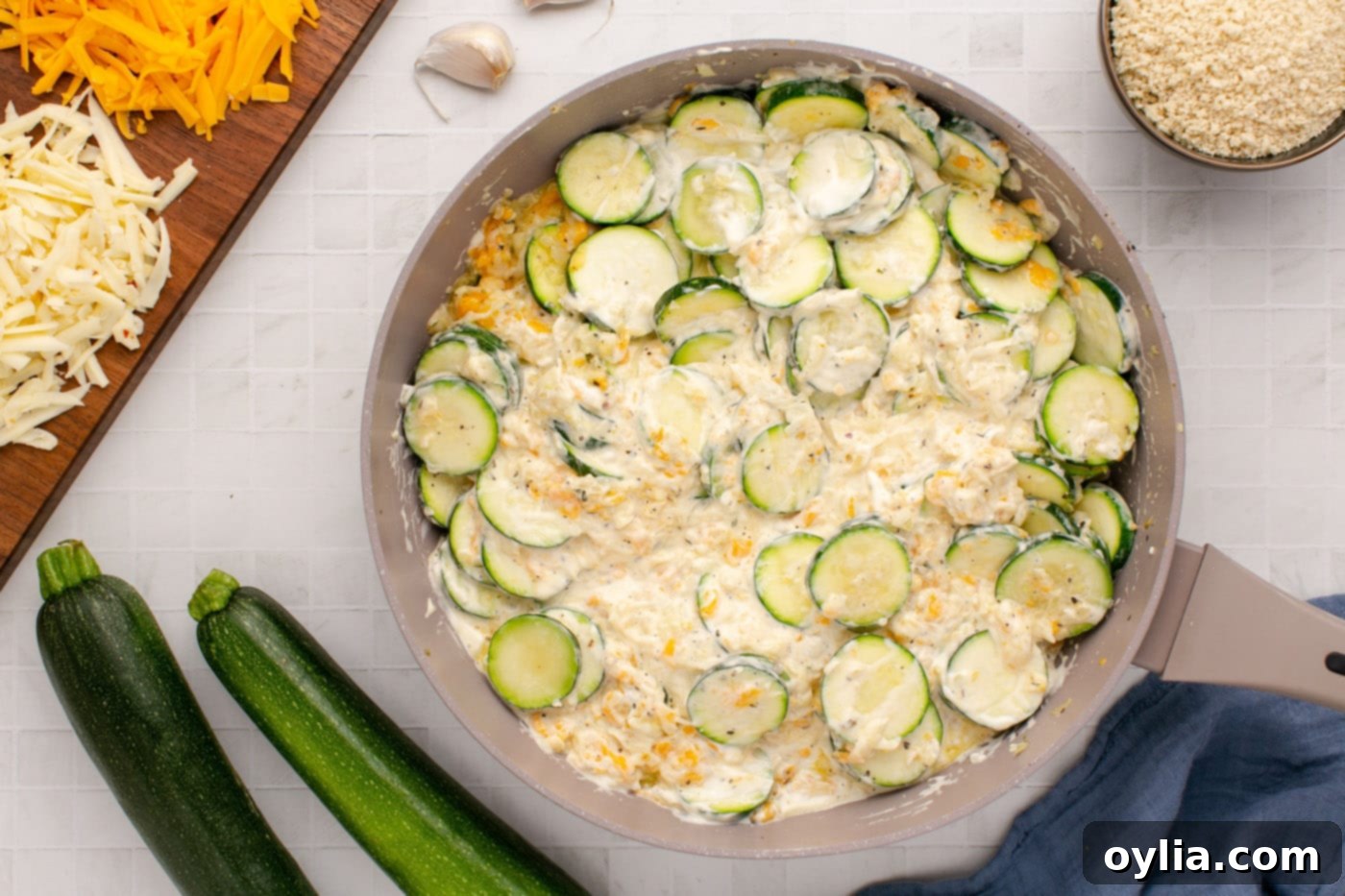 The fully combined creamy cheesy zucchini mixture in a skillet, ready for the baking dish.