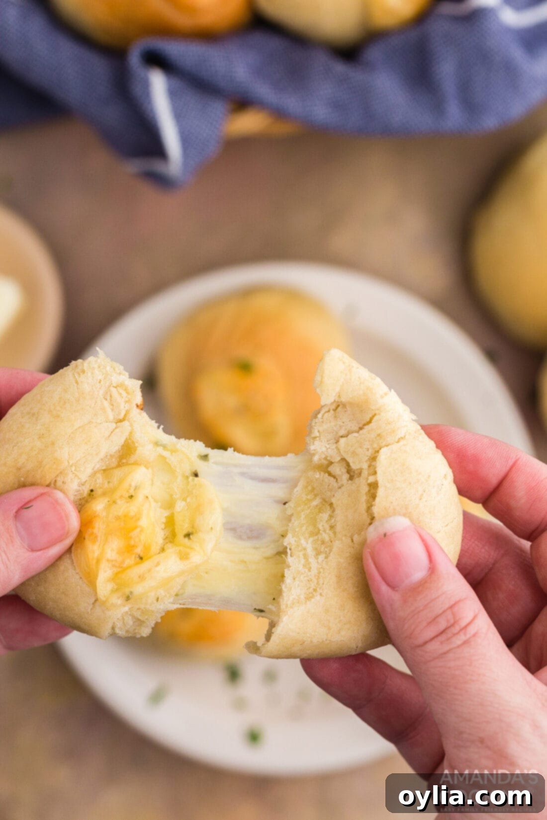 Golden Garlic Cheese Rolls 3 hands pulling a garlic cheese roll apart, showing melted, stretchy cheese inside