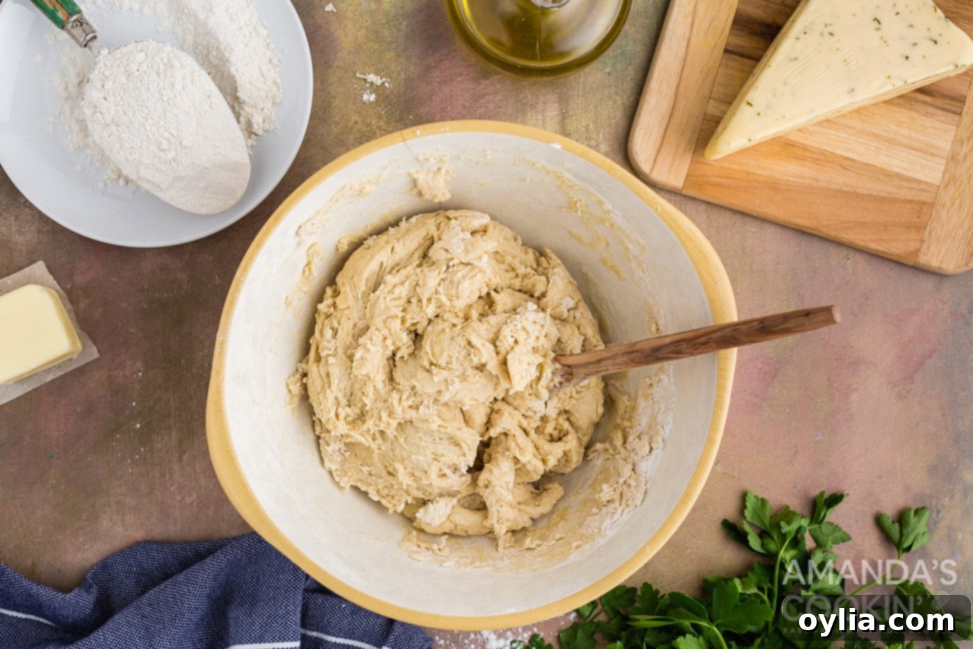 Golden Garlic Cheese Rolls 7 dough in a bowl with wooden spoon after mixing
