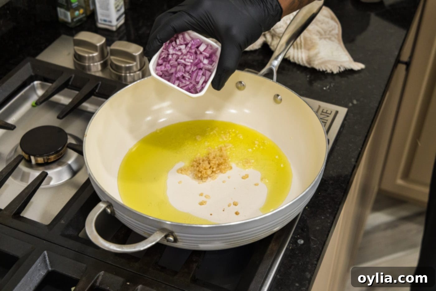 adding shallots to pan with oil and garlic
