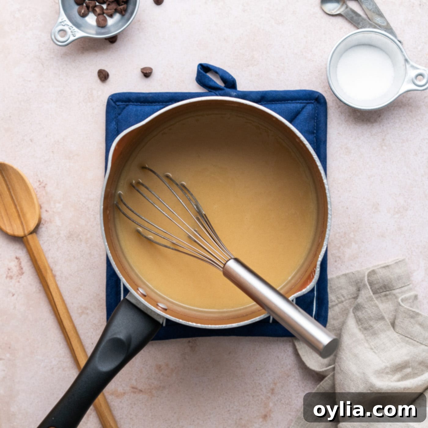 whisking homemade caramel in a saucepan over heat