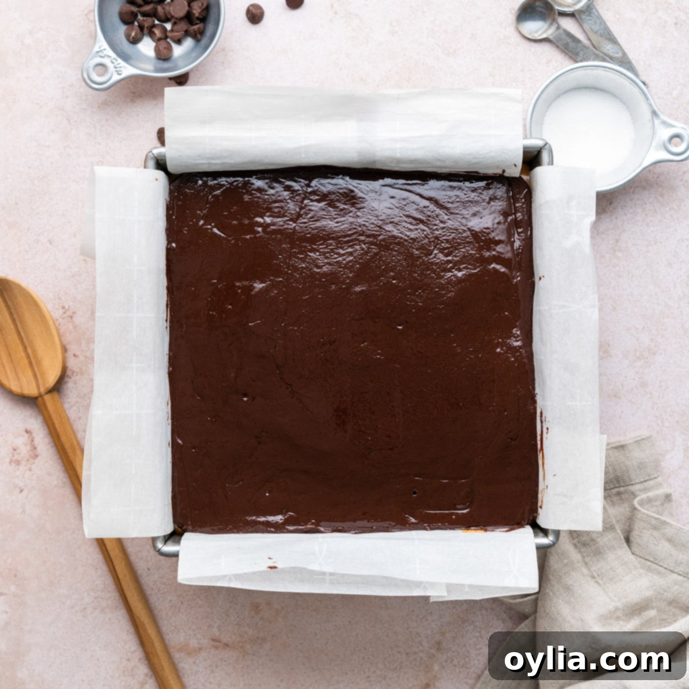 overhead view of chocolate ganache on top of caramel and brownies, smoothed out