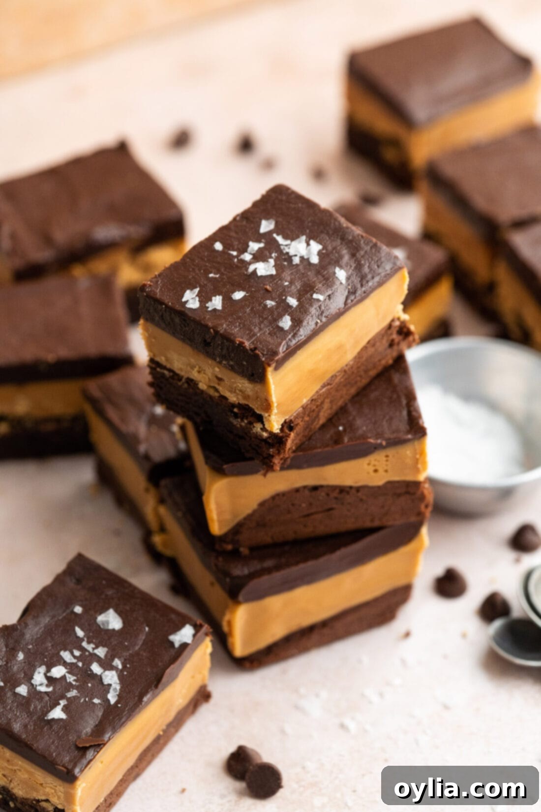Ultimate Indulgence Brownies 3 Stack of three Millionaire Brownies with others around it, showcasing their rich, multi-layered appearance