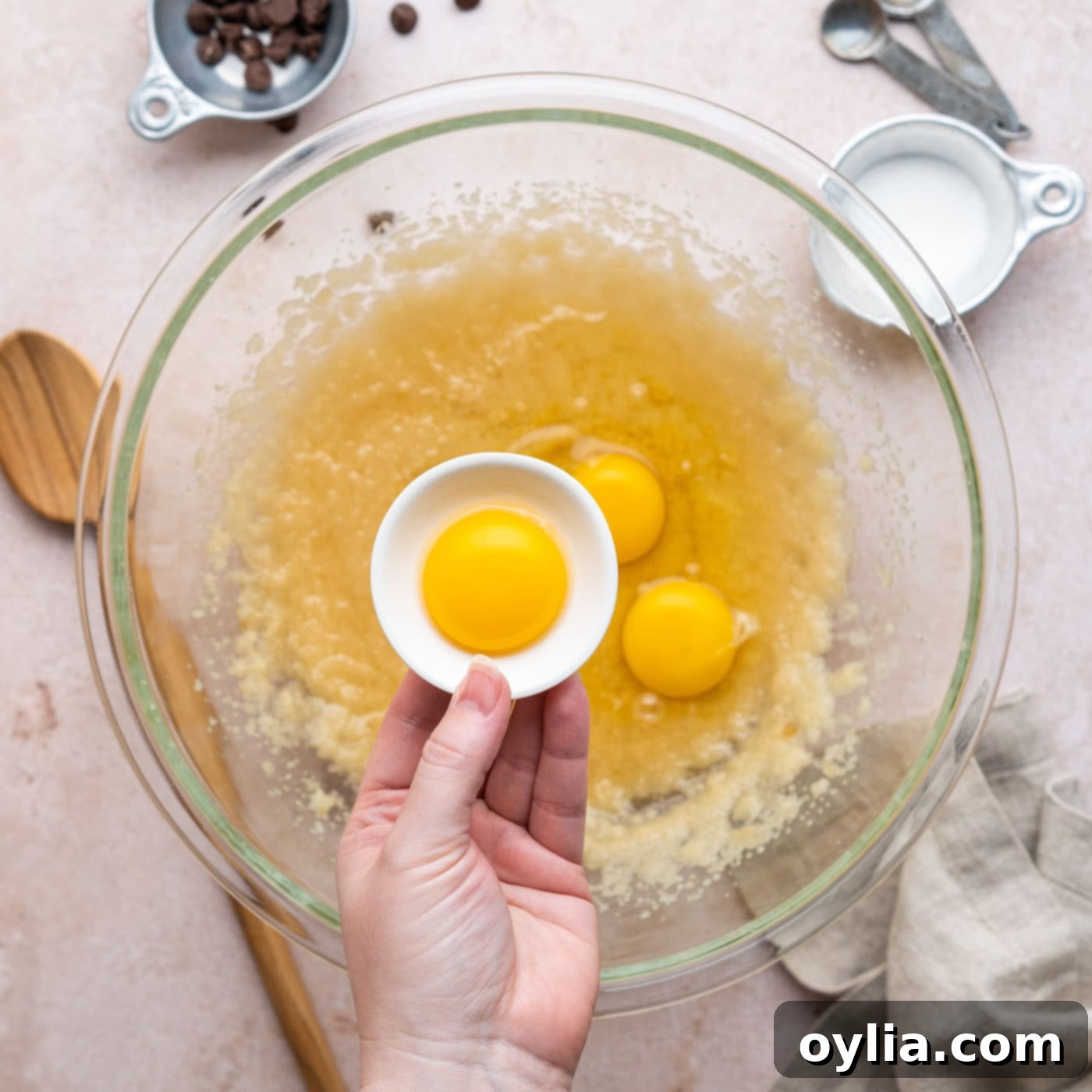 adding egg yolk to brownie batter mixture in a bowl