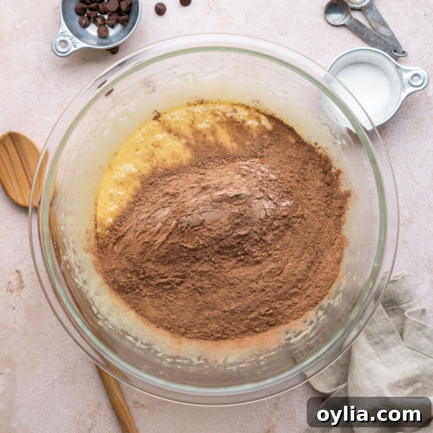 adding dry ingredients to wet ingredients for brownies in a bowl