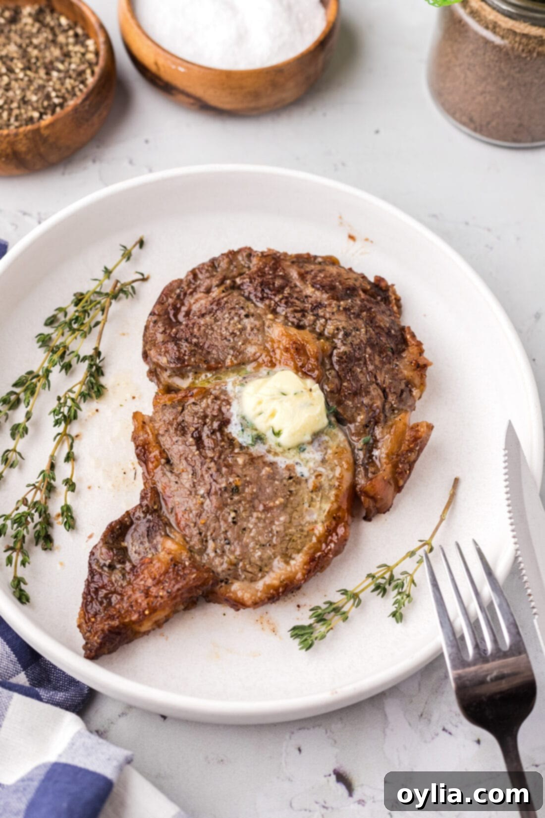 Air Fried Steak Perfection 3 A perfectly cooked Air Fryer Steak on a white plate, ready to be served, garnished with fresh herbs.