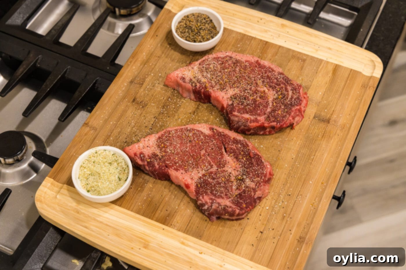 ribeye steaks on cutting board seasoned with garlic salt and steak seasoning, ready for the air fryer