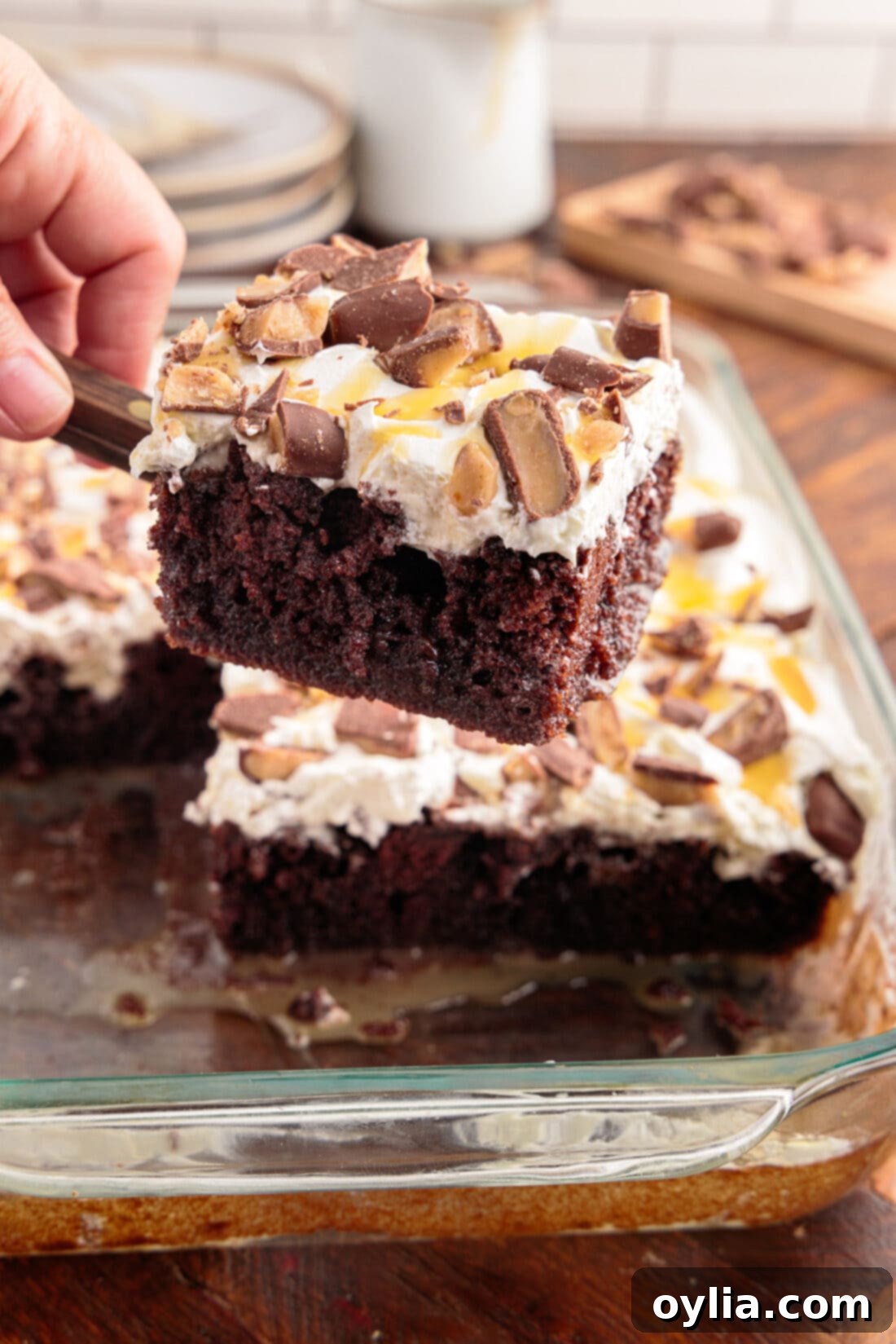 Slice of Better Than Sex Cake being lifted out of a pan, showcasing its layers and toppings.
