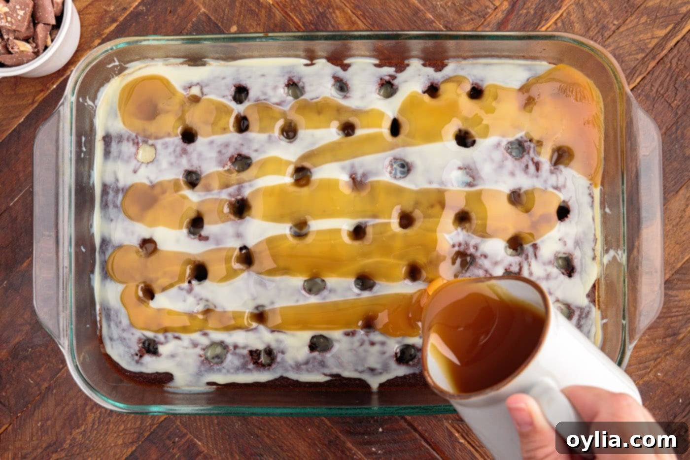 Caramel sauce being poured over the sweetened condensed milk, soaking into the cake.