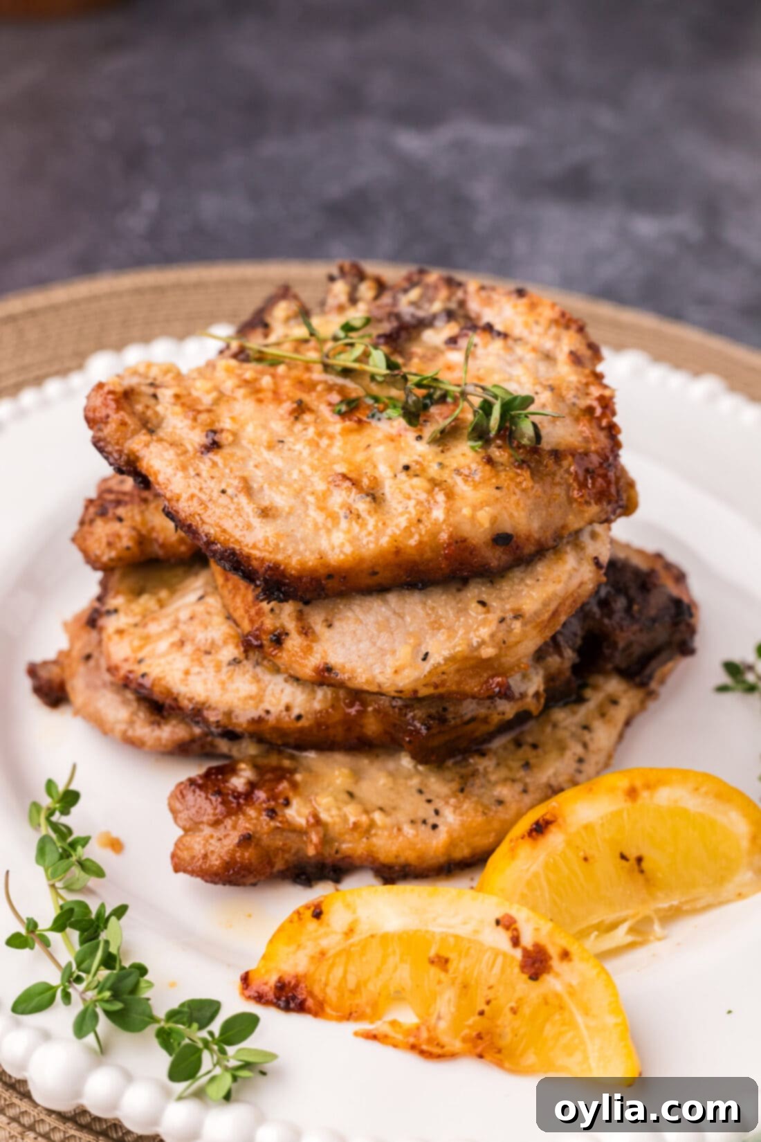 Stack of juicy Garlic Butter Pork Chops on a white plate, garnished and ready to be served