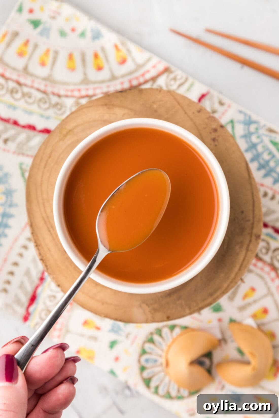 Tangy Sweet Glaze 2 Spoonful of Sweet and Sour Sauce held over a bowl of Sweet and Sour Sauce