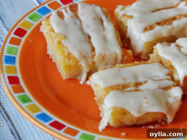 A close up photo of tropical dream dessert bars on an orange plate, showcasing their vibrant color and glaze.