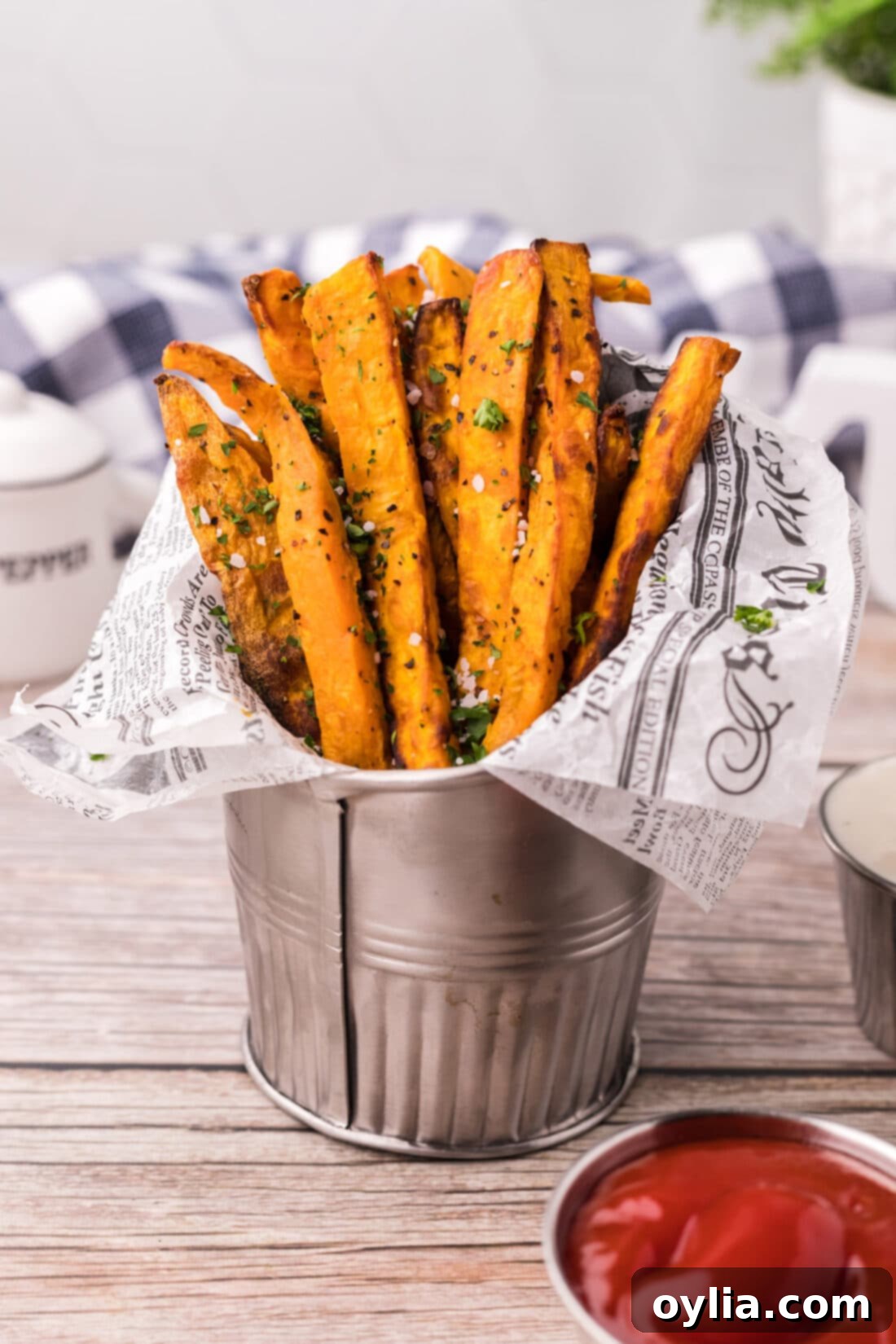 Air Fryer Sweet Potato Fries served in a metal fry cup with parchment paper, ready to be dipped.