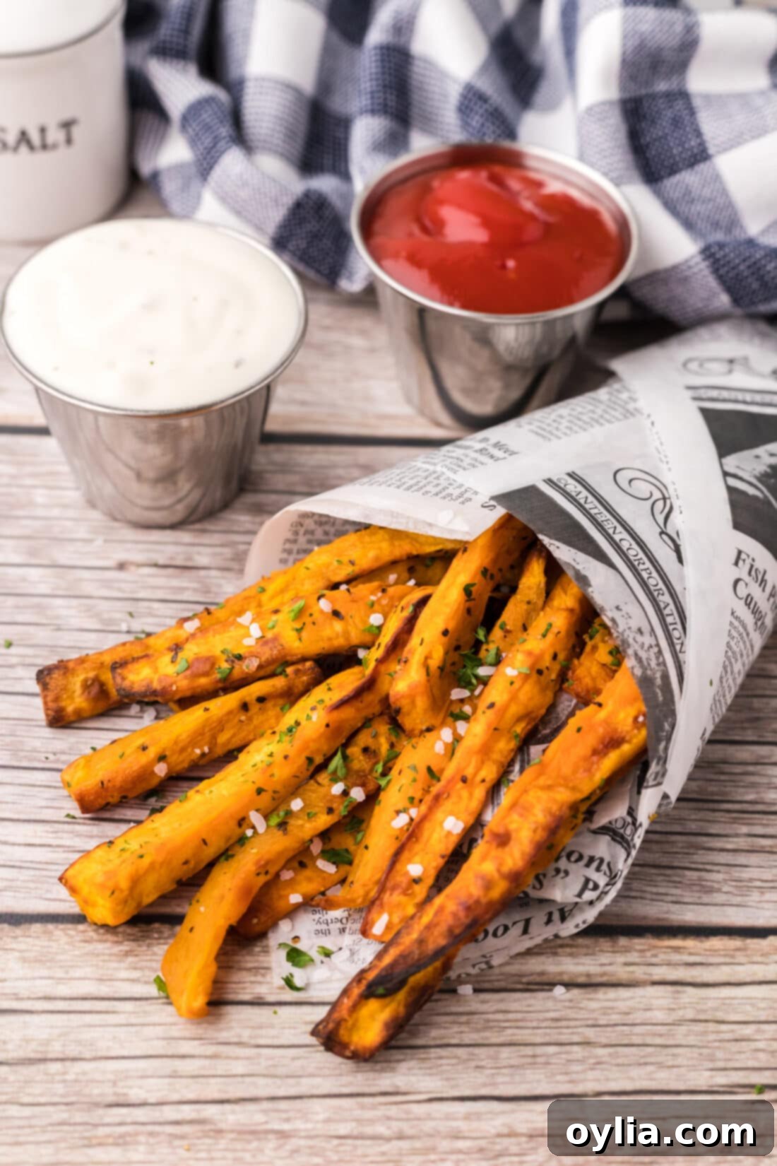 Air Fryer Sweet Potato Fries wrapped in parchment paper, showcasing their golden-brown crispness.