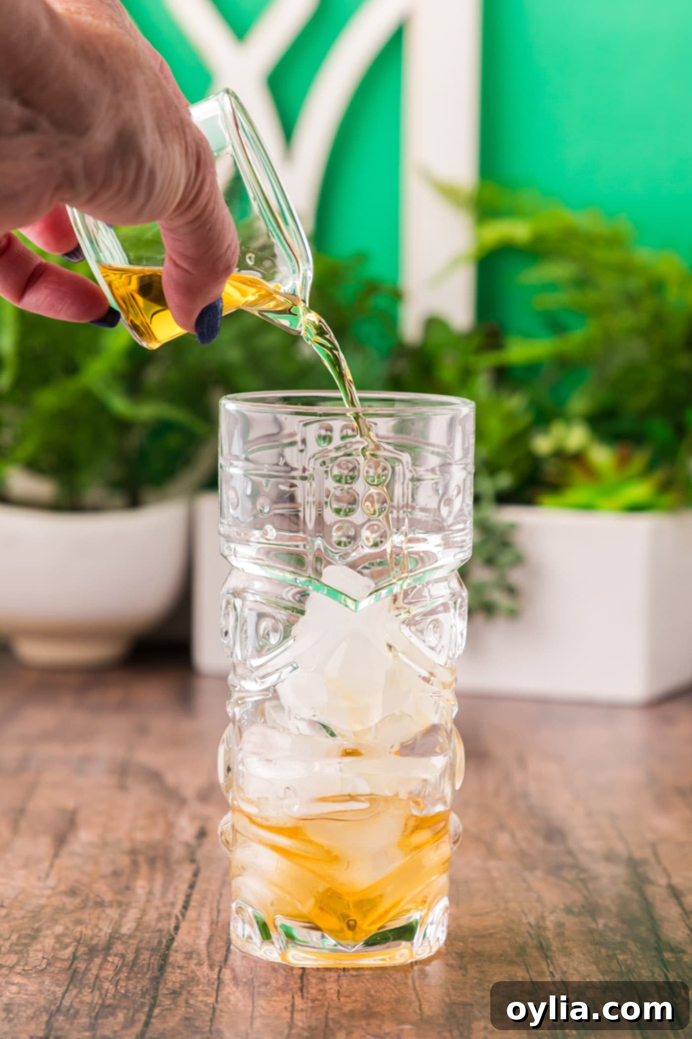 pouring rum into a glass filled with ice cubes