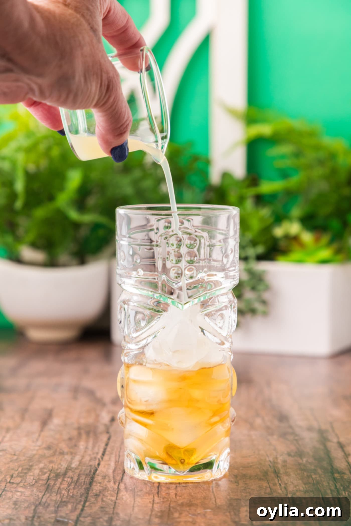 adding fresh lime juice to a glass of rum and ice