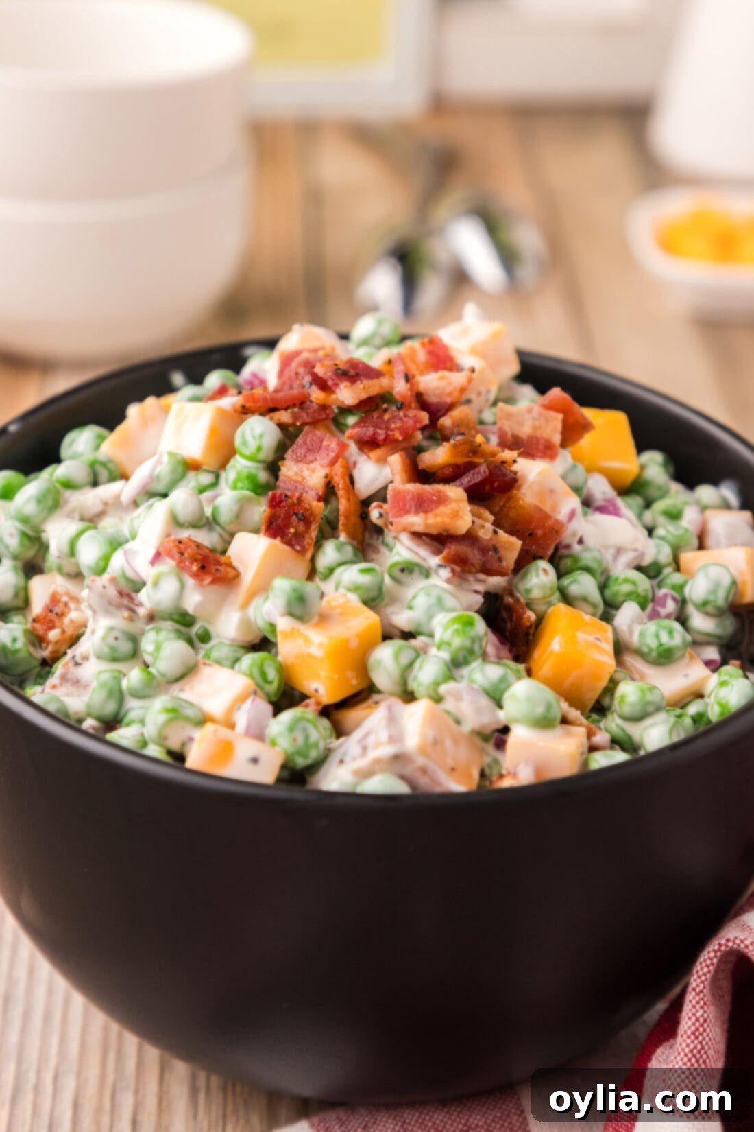 Close up photo of Creamy Pea Salad in a rustic bowl, garnished with fresh herbs and crispy bacon bits