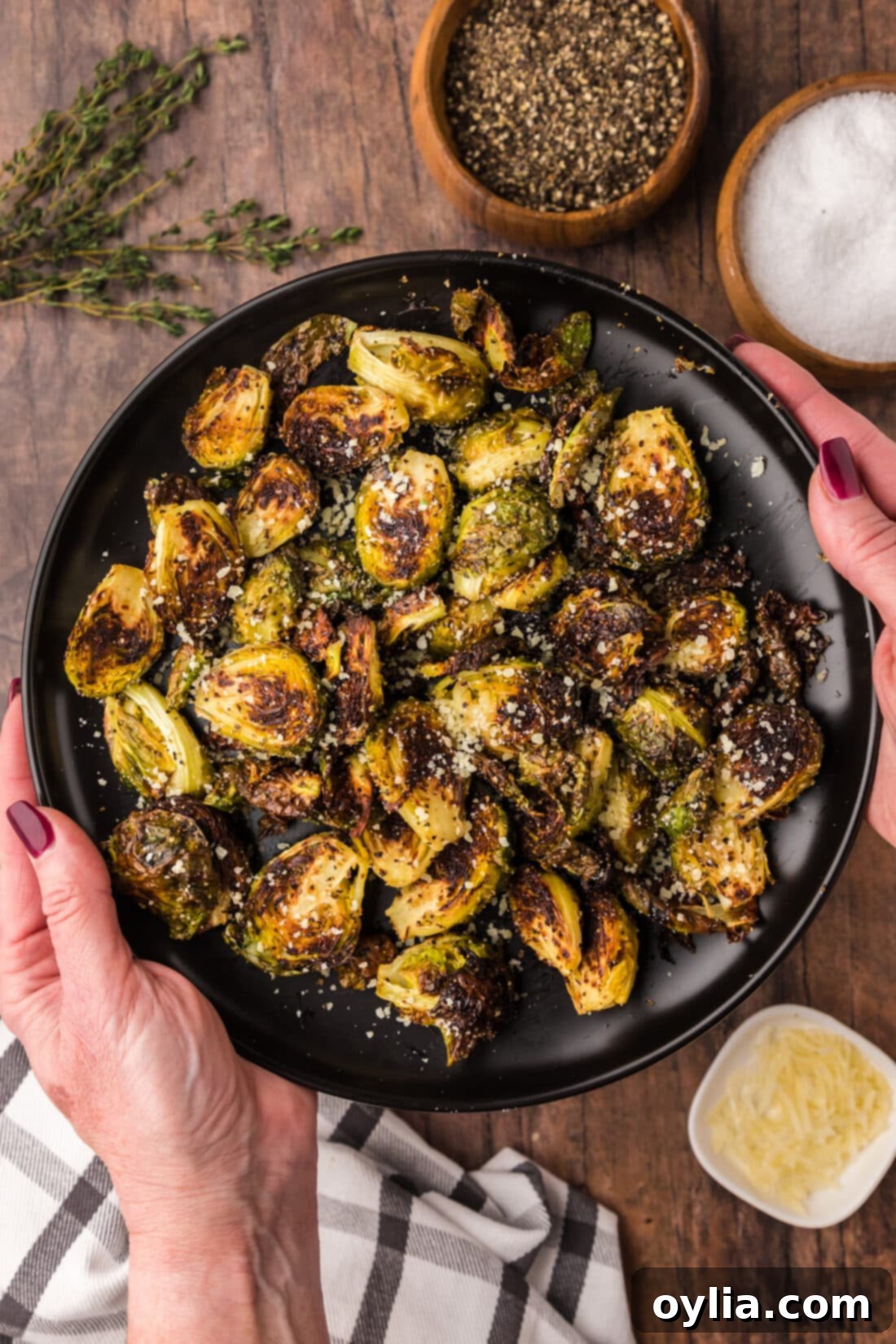 Crispy Roasted Brussels Sprouts 12 Hands holding a plate of Roasted Brussel Sprouts topped with parmesan, a delicious and healthy side dish