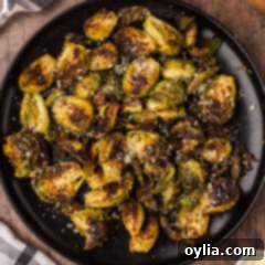 Crispy Roasted Brussels Sprouts 13 Close up photo of a plate of Roasted Brussel Sprouts, golden brown and garnished with herbs