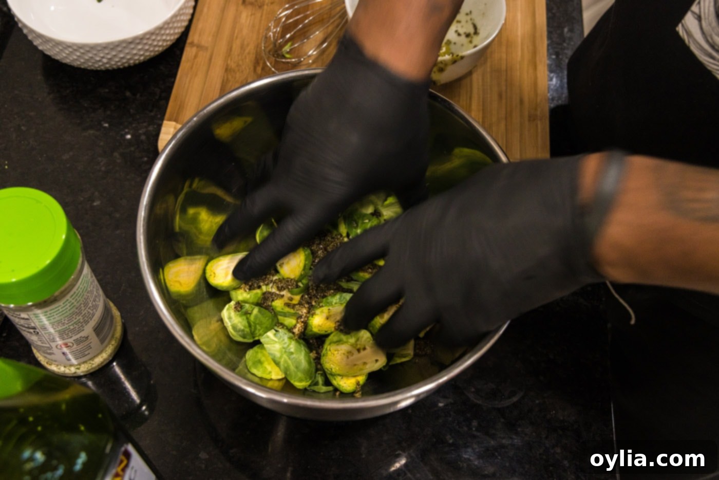 hands mixing brussels sprouts with oil and seasonings in a bowl, ensuring even coating