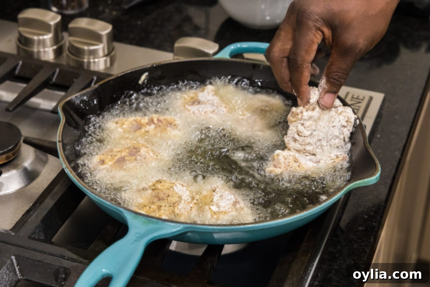 adding dredged chicken thighs to hot oil