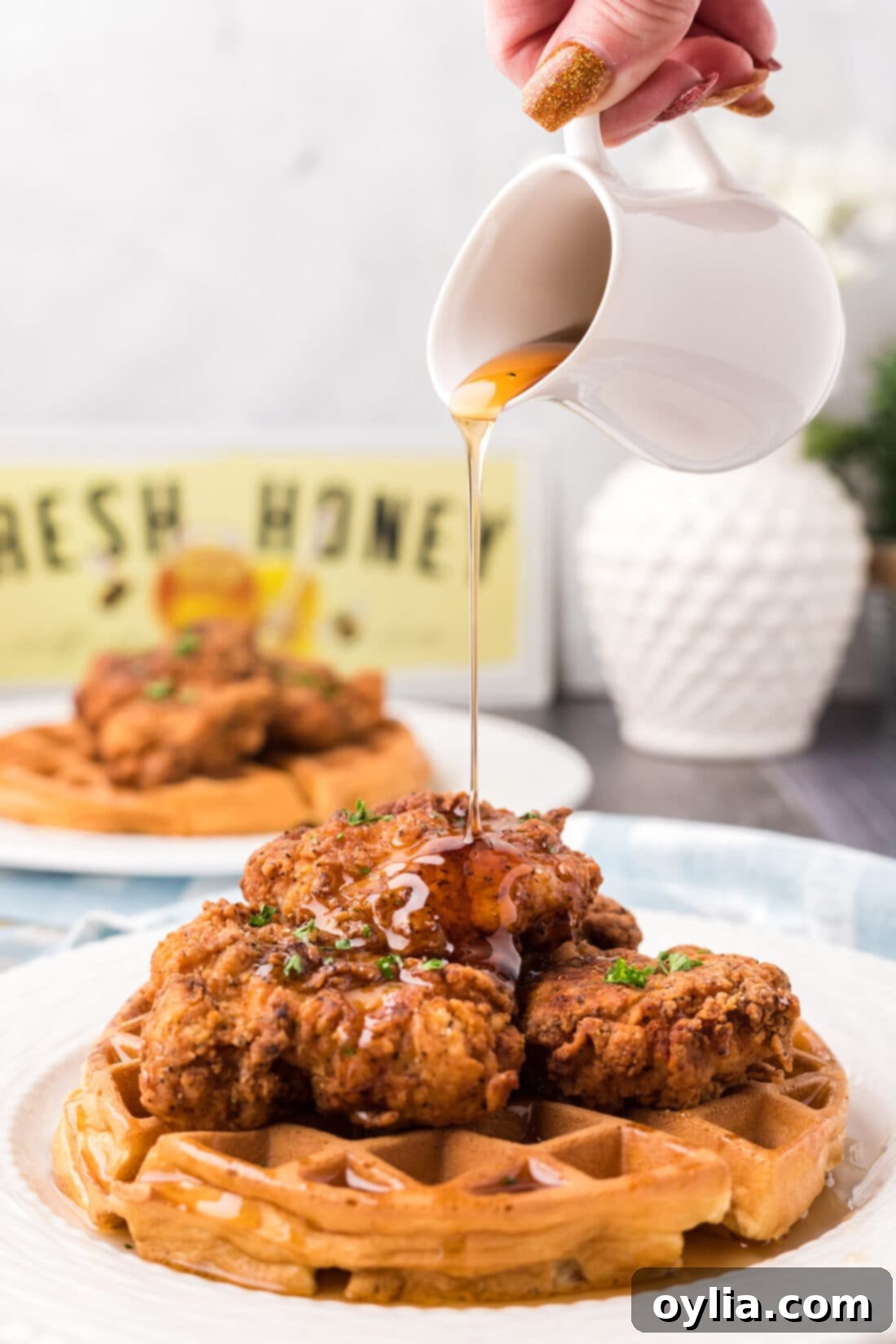 Syrup being drizzled over a plate of Chicken and Waffles