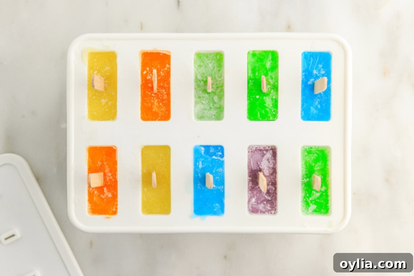 A popsicle mold filled with colorful Jello, now frozen solid and ready for removal from the freezer.