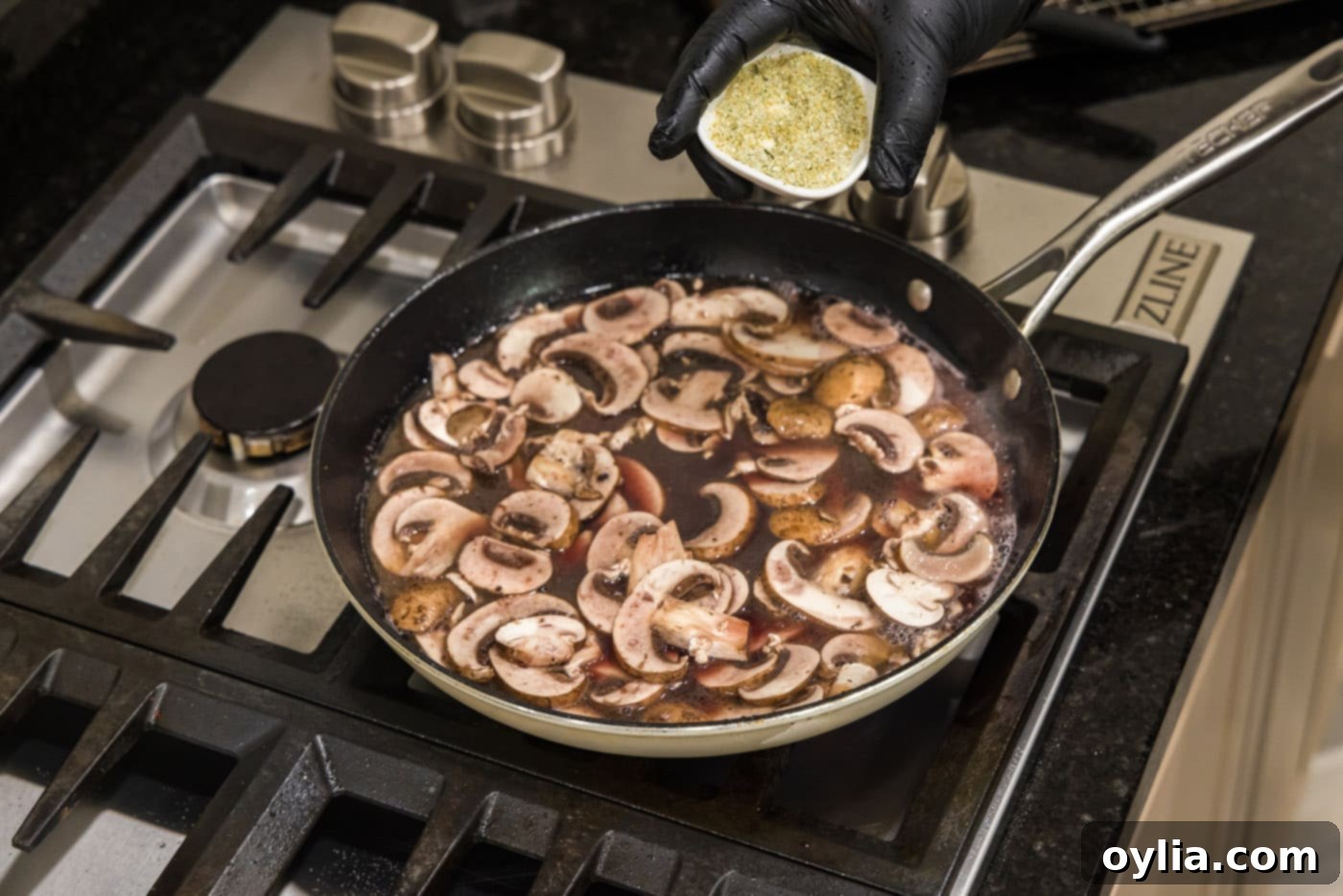Adding chicken stock and sliced mushrooms to the Marsala wine sauce.