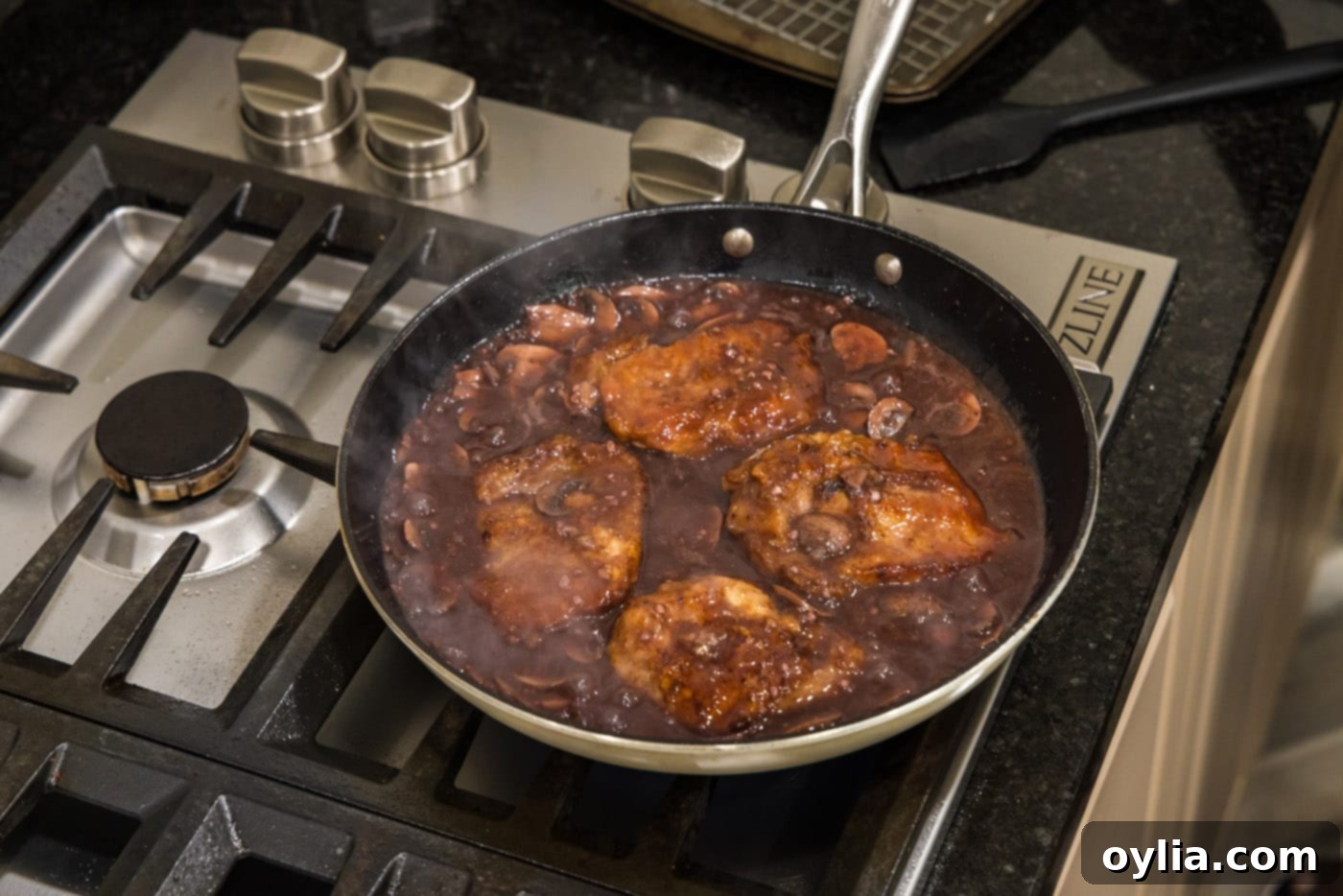 Veal Marsala cutlets gently simmering in the rich mushroom sauce in a skillet.