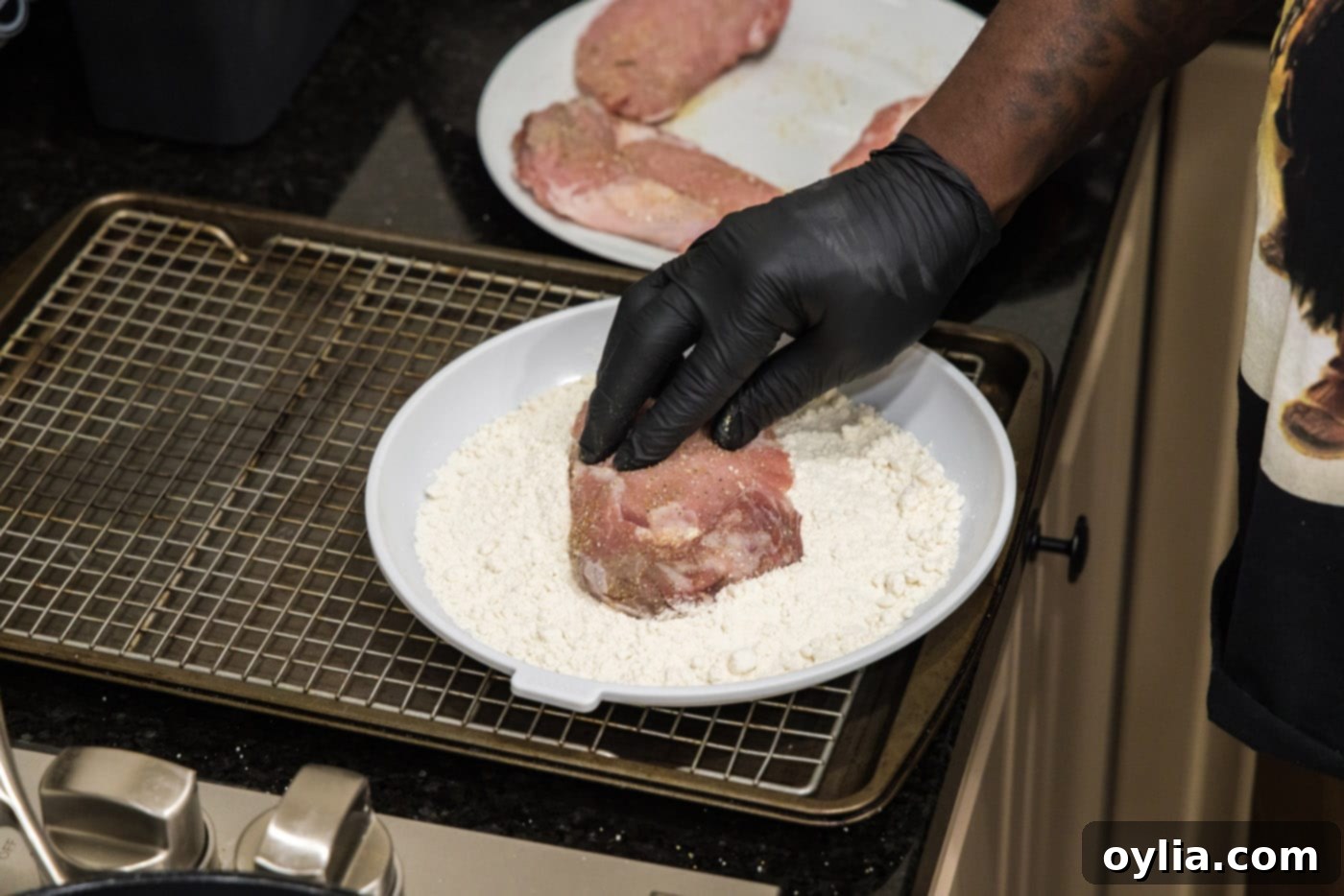 Pressing veal chop into flour for dredging.
