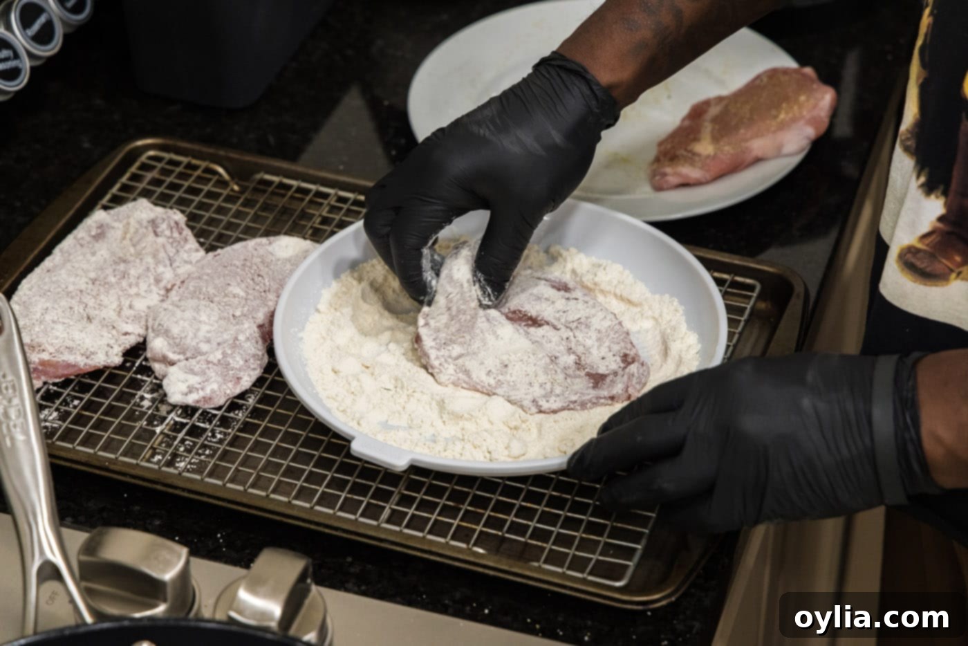 Dredging veal cutlet evenly in flour on a shallow plate.