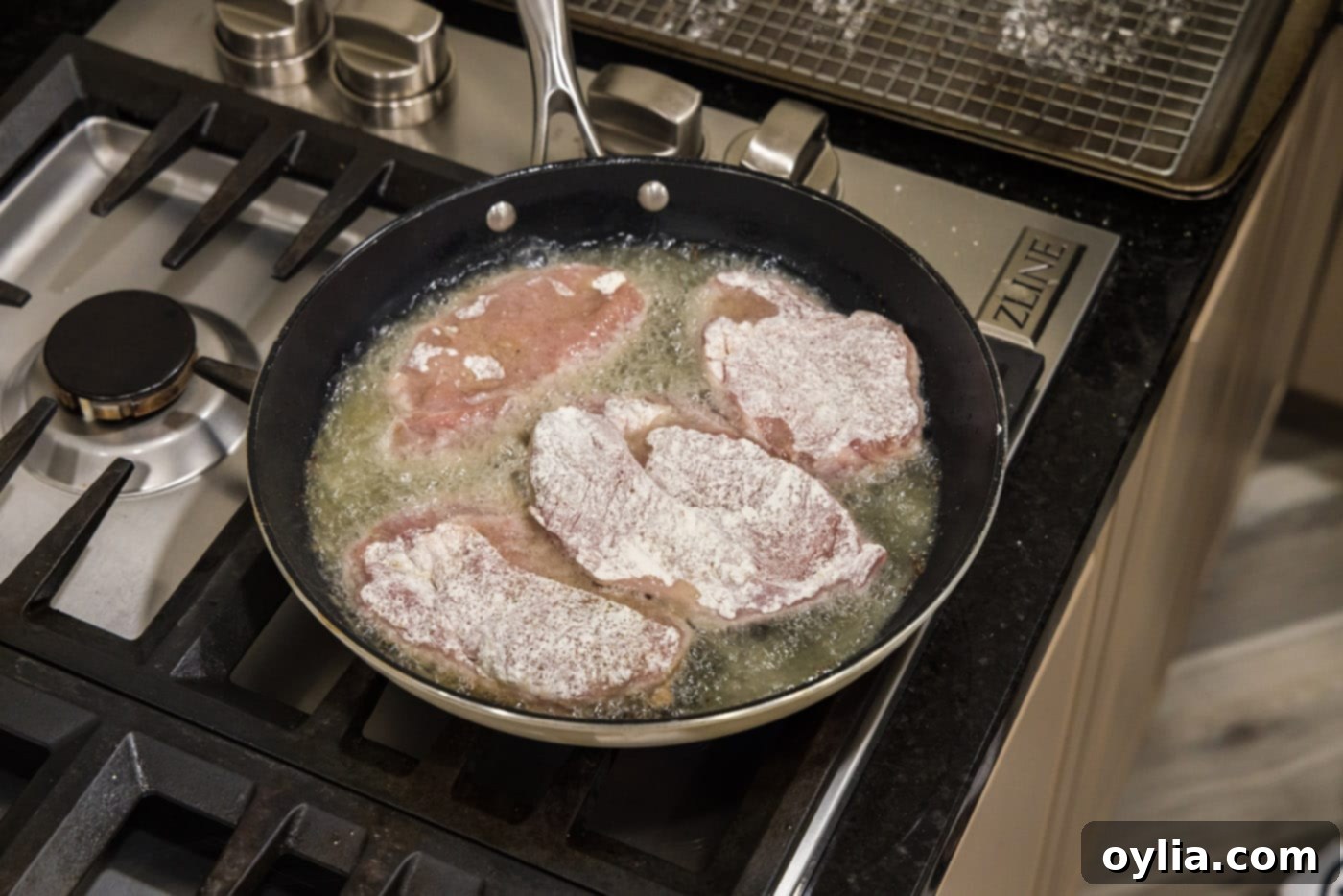 Cooking flour-coated veal cutlets in a hot skillet of oil.