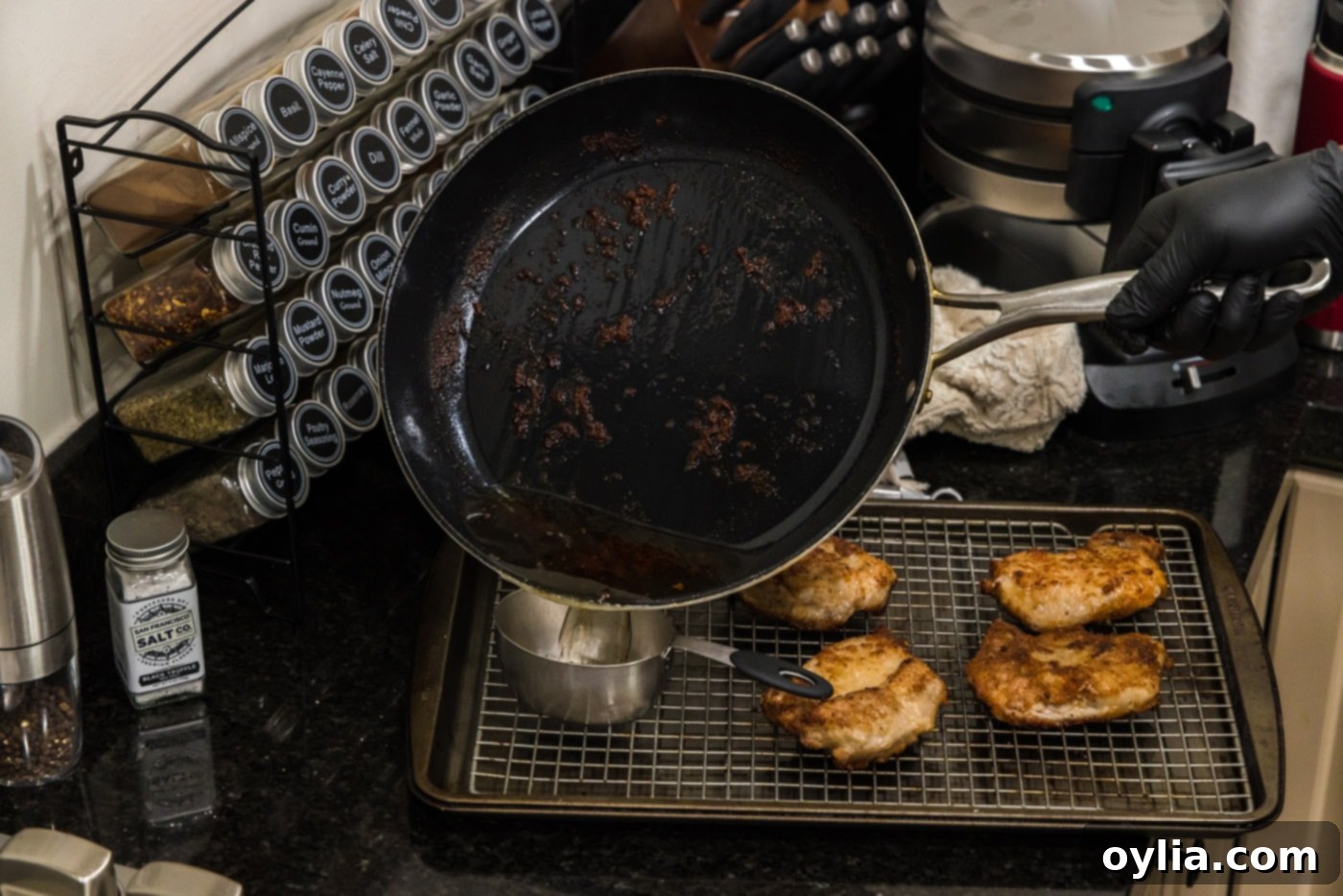 Pouring pan drippings from skillet into a measuring cup.