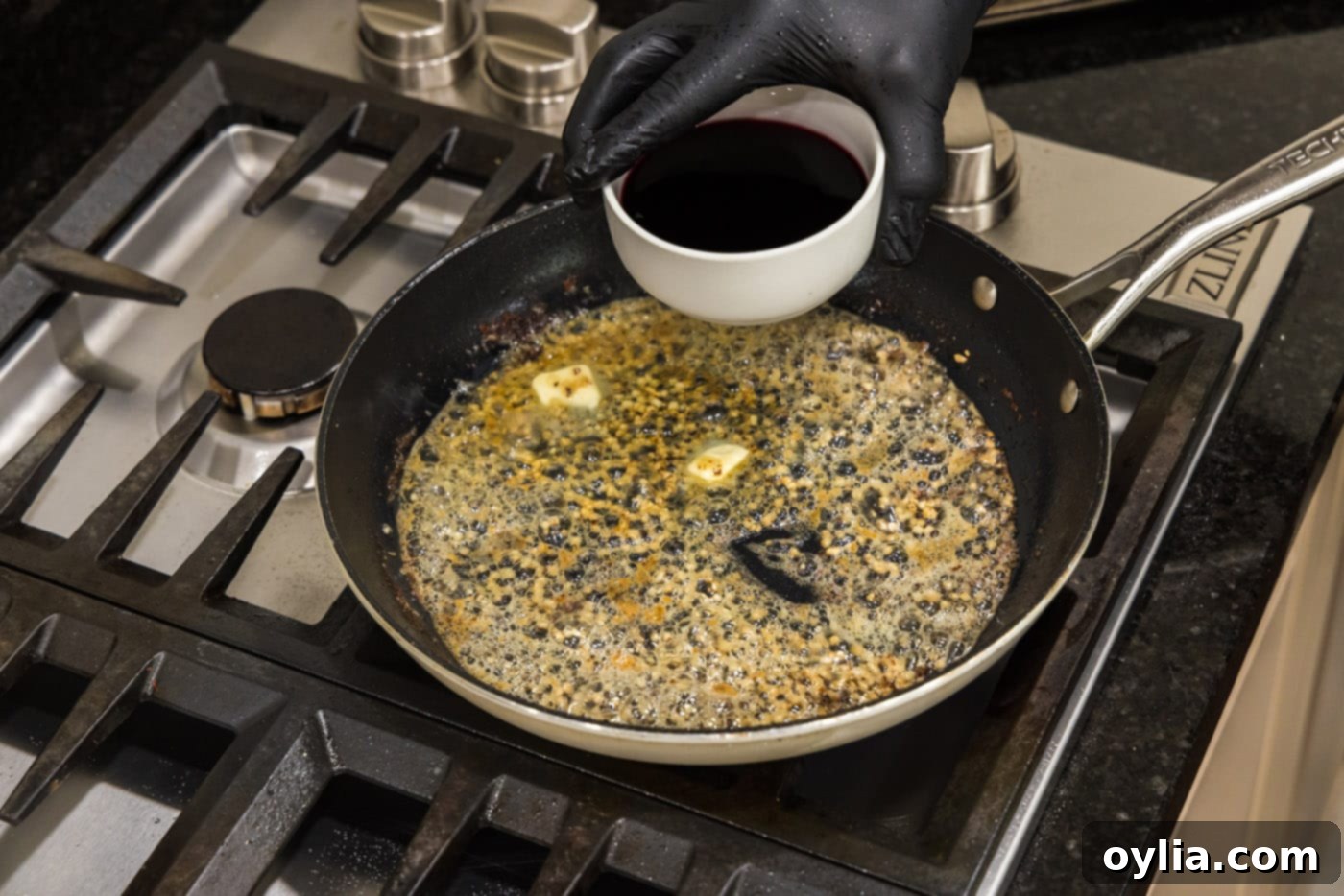 Adding Marsala wine to a skillet with melted butter and minced garlic.