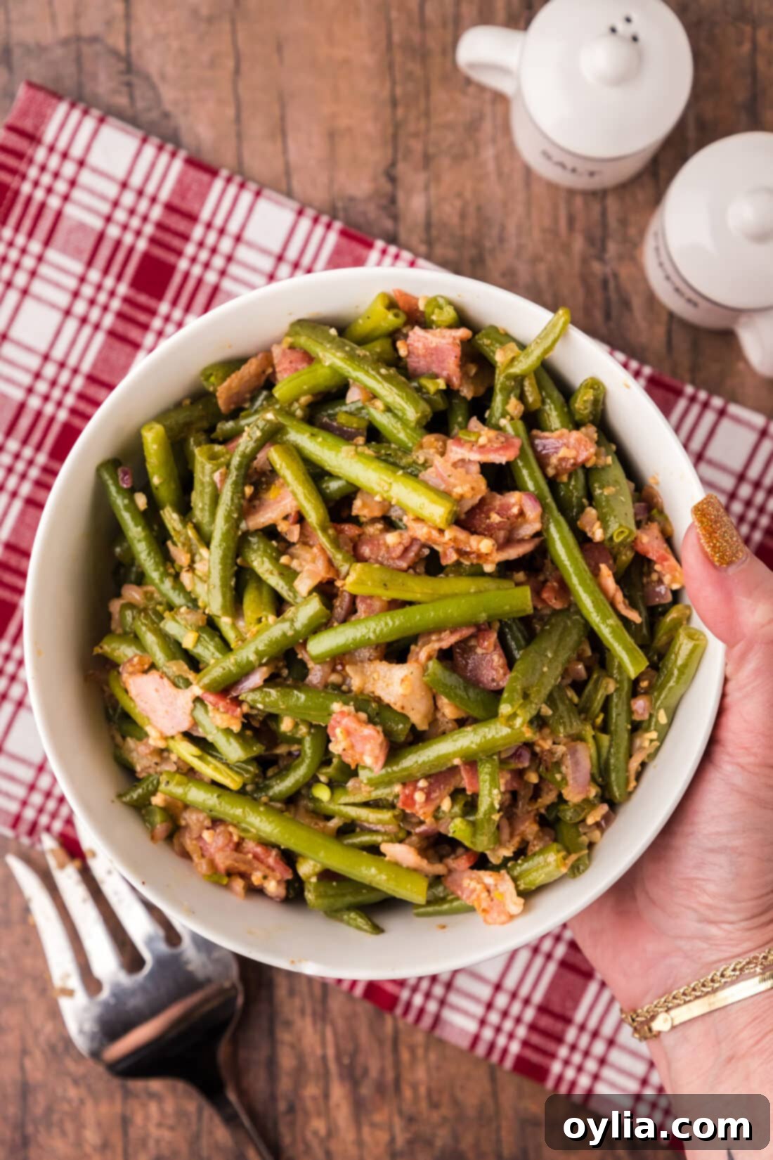 Southern Style Stewed Green Beans 2 Hand holding a bowl of tender Southern Green Beans with bacon