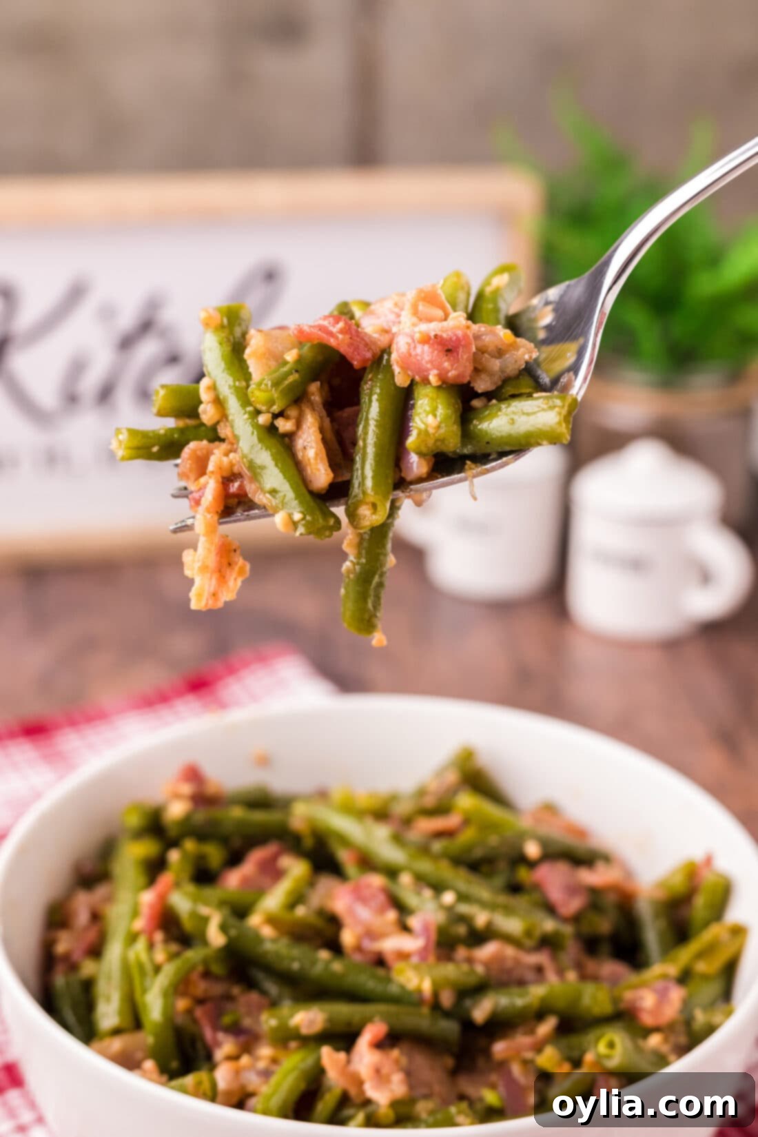 Southern Style Stewed Green Beans 3 Fork full of Southern Green Beans with bacon being lifted out of a bowl