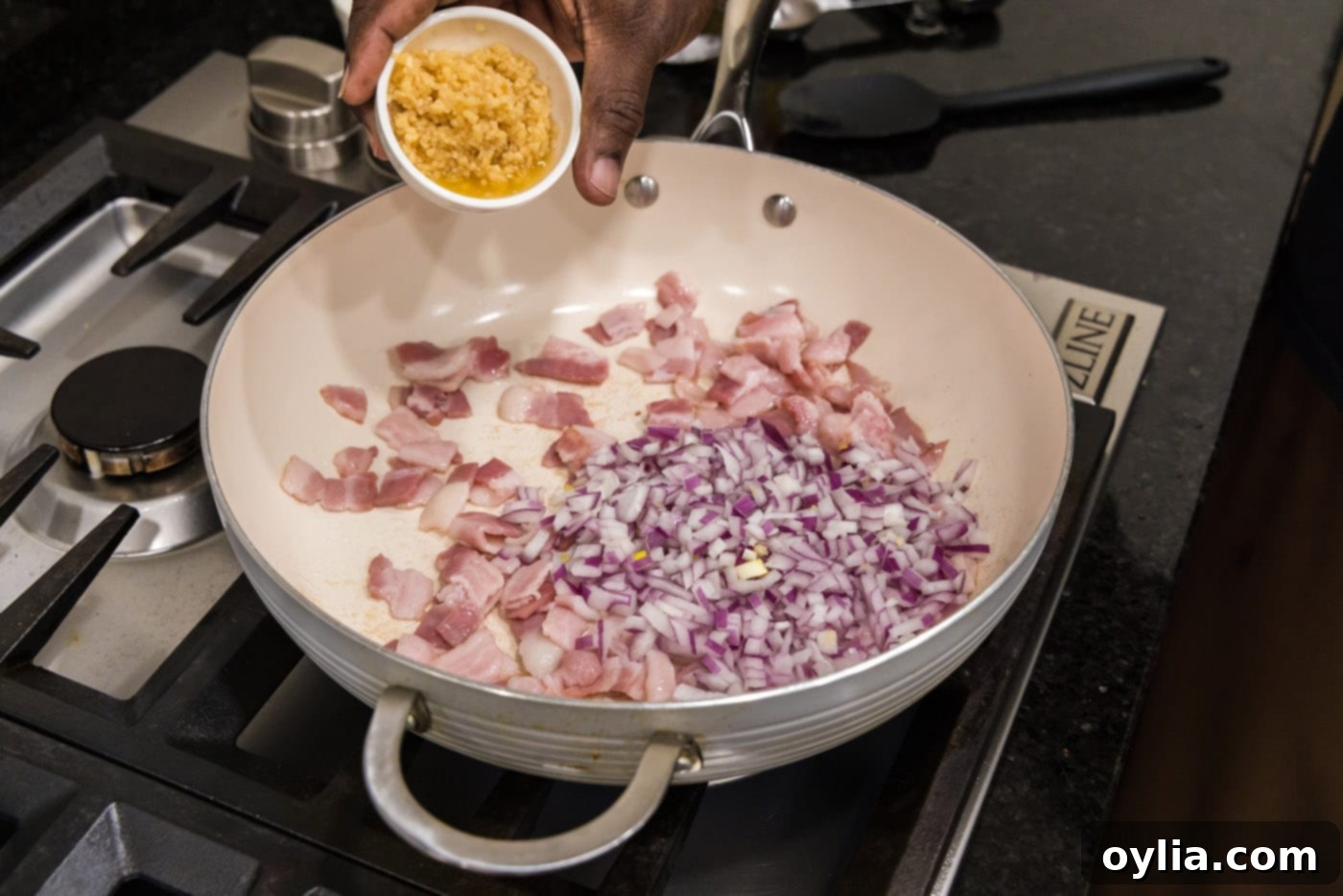 Adding minced garlic to a skillet with chopped shallots and tender bacon