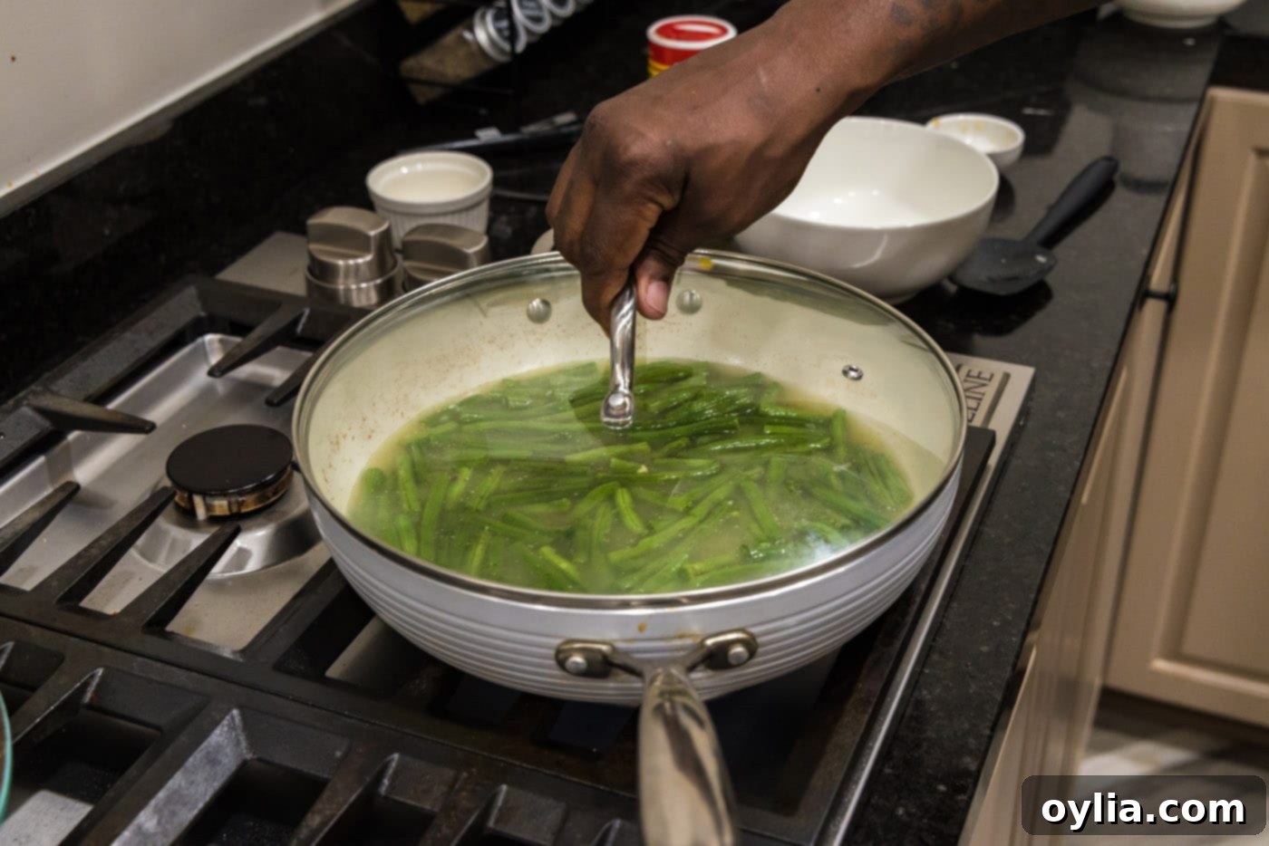 Placing a lid on a skillet to cook green beans