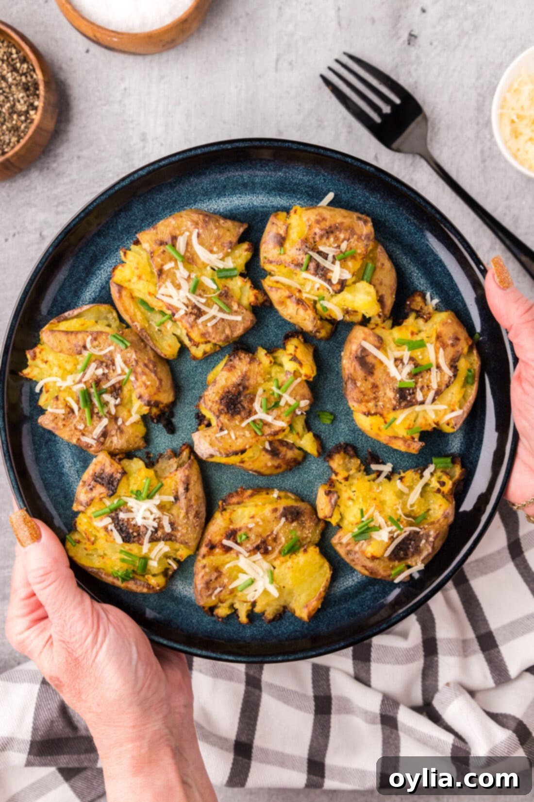 Hands holding up a plate of Smashed Potatoes