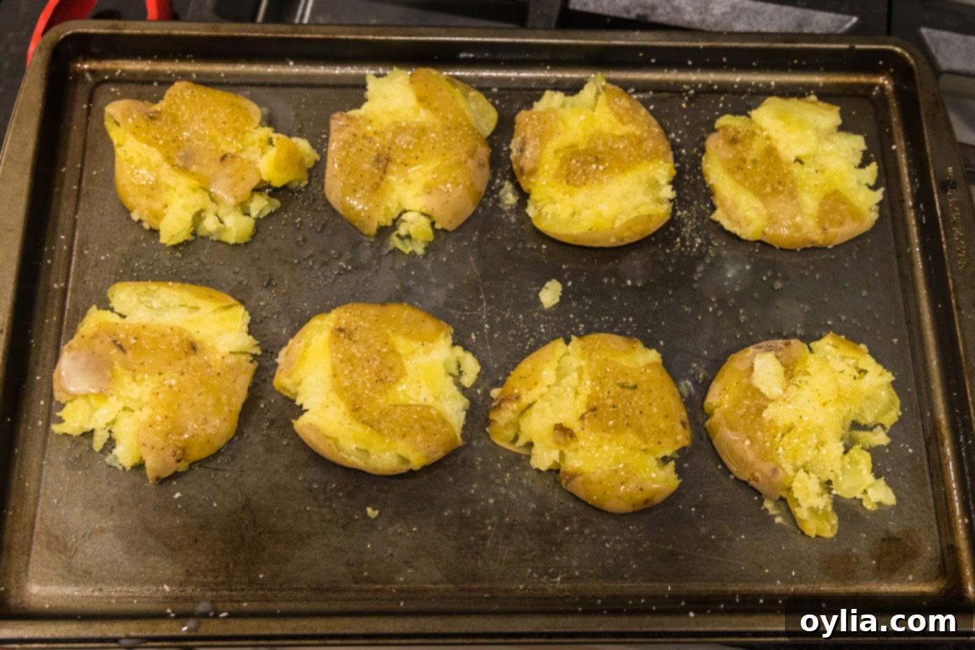 seasoned and butter basted smashed potatoes on a baking sheet