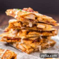 Close up photo of a stack of Chicken Bacon Ranch Quesadilla triangles, highlighting the cheesy, meaty filling.